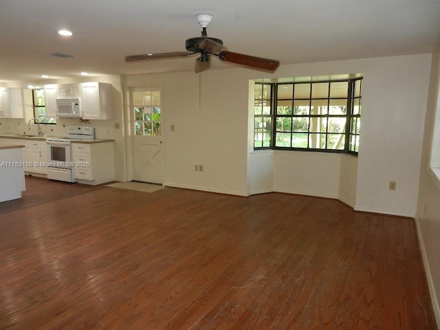 unfurnished living room with a ceiling fan, dark wood finished floors, plenty of natural light, and a sink