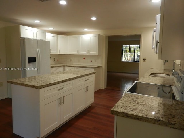 kitchen featuring light stone countertops, white fridge with ice dispenser, electric stove, dark wood-type flooring, and backsplash