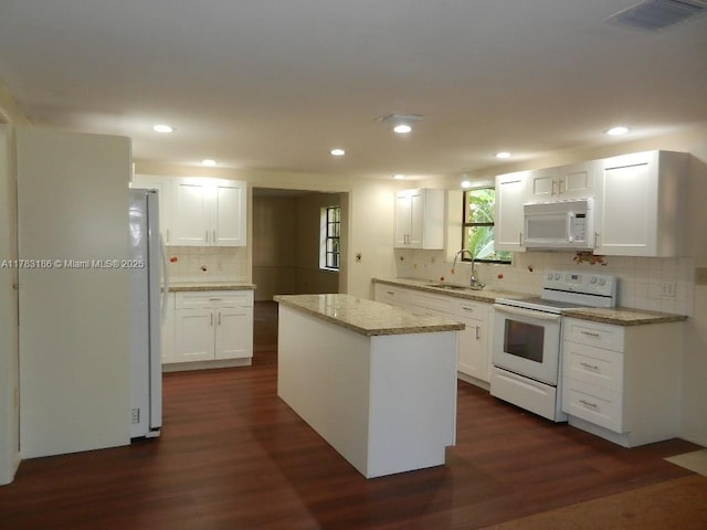 kitchen featuring visible vents, tasteful backsplash, a sink, white appliances, and dark wood-type flooring