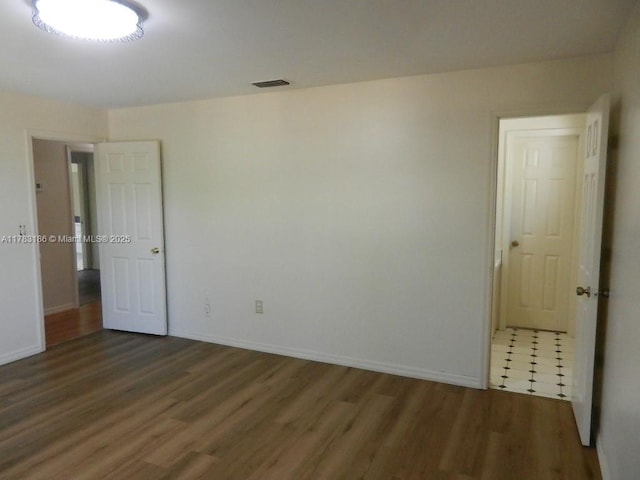 empty room featuring visible vents, baseboards, and wood finished floors