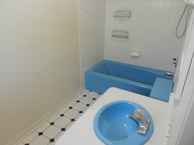 bathroom featuring baseboards, washtub / shower combination, and a sink