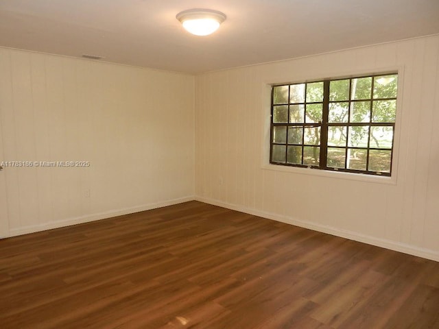 spare room with baseboards and dark wood finished floors