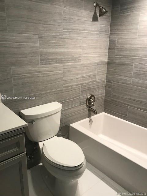 20301 W Country Club Dr Unit 830, Aventura, FL 33180 - full bath with vanity, shower / tub combination, tile patterned flooring, toilet, and tile walls