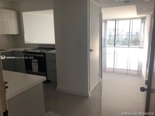20301 W Country Club Dr Unit 830, Aventura, FL 33180 - kitchen featuring light tile patterned floors, white cabinets, modern cabinets, light countertops, and black / electric stove