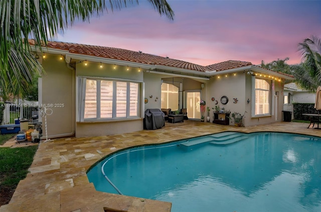 4060 SW 152nd Ave, Miramar, FL 33027 - back of house at dusk featuring an outdoor pool, a patio area, stucco siding, and a tile roof