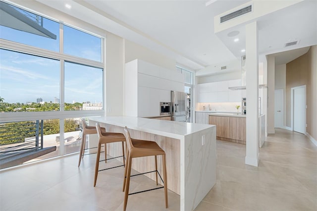 2001 Meridian Ave Unit 514, Miami Beach, FL 33139 - kitchen featuring stainless steel fridge with ice dispenser, a peninsula, white cabinets, visible vents, and modern cabinets