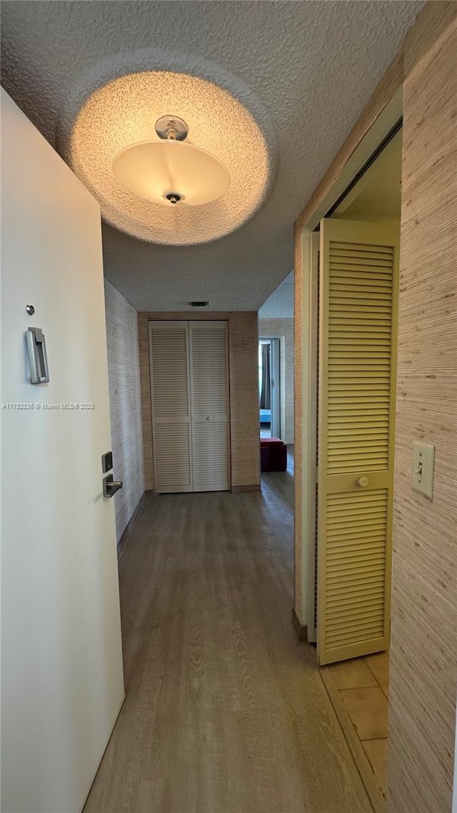 hall with wood finished floors and a textured ceiling