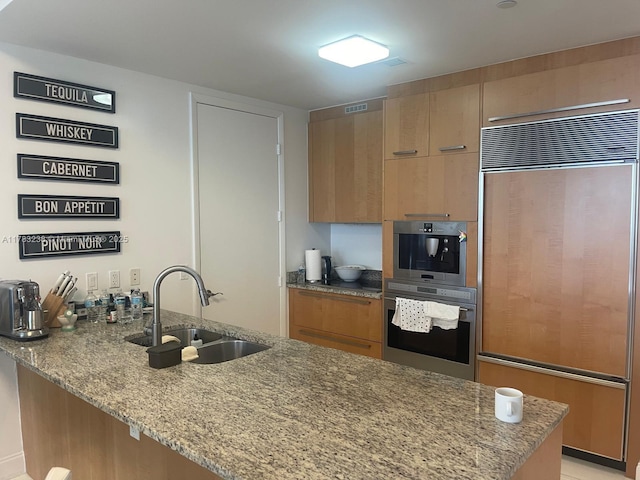15811 Collins Ave Unit 1402, Sunny Isles Beach, FL 33160 - kitchen with paneled built in fridge, a sink, light stone countertops, a peninsula, and stainless steel double oven