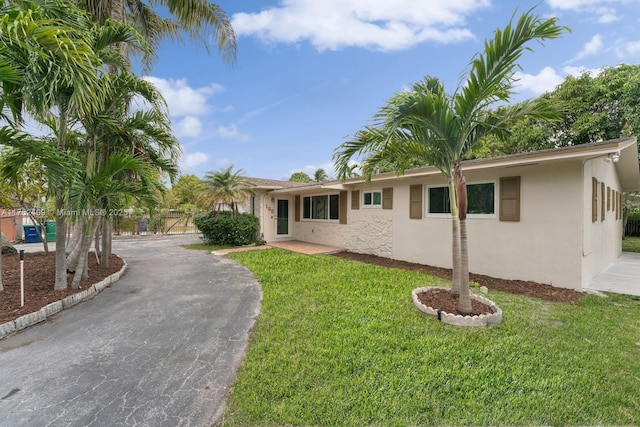 ranch-style home with a front yard, driveway, and stucco siding