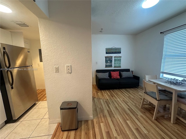 interior space featuring a textured wall, light wood-style floors, and baseboards