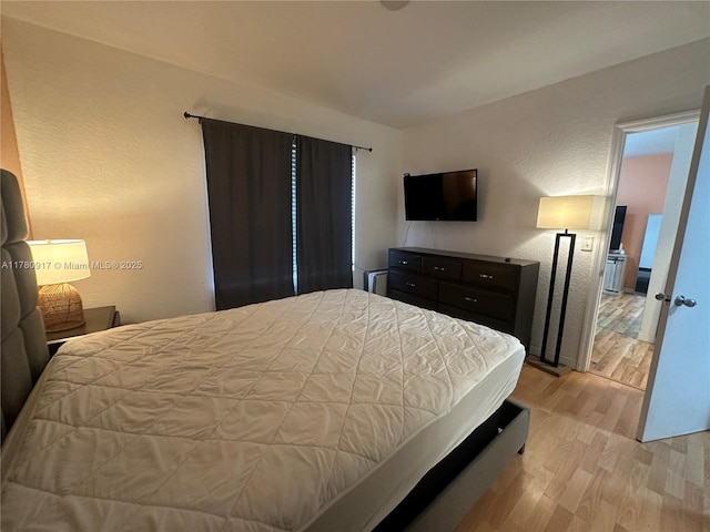 bedroom with a textured wall and light wood-style flooring