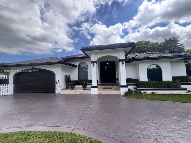 mediterranean / spanish home with driveway, stucco siding, an attached garage, and a tile roof