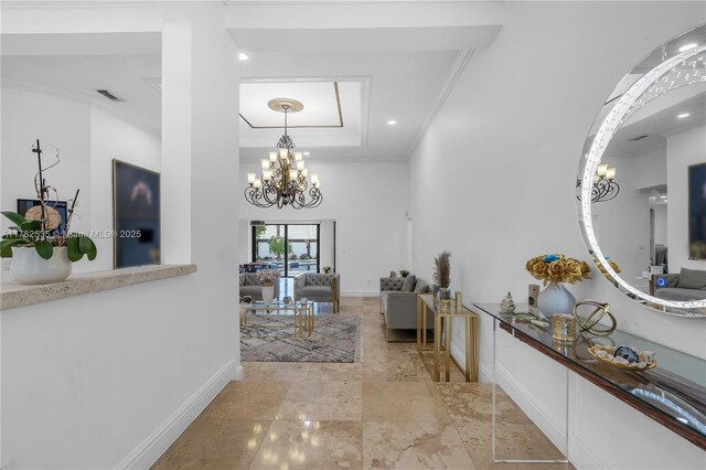 hall featuring a chandelier, baseboards, ornamental molding, and a raised ceiling
