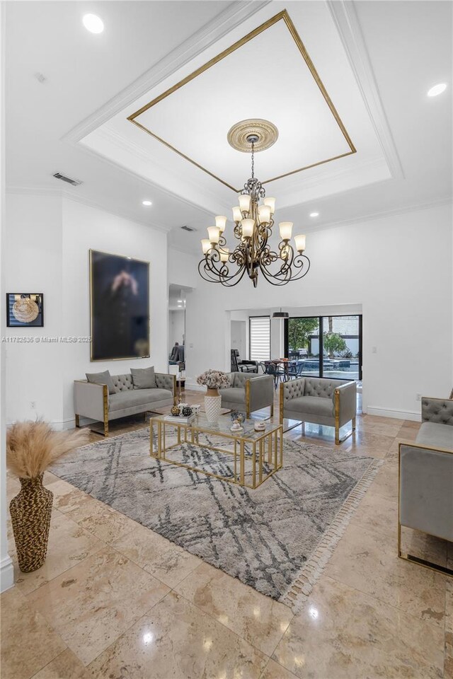 living area featuring crown molding, a tray ceiling, baseboards, and an inviting chandelier