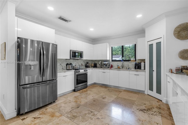 kitchen featuring ornamental molding, light countertops, white cabinetry, stainless steel appliances, and backsplash