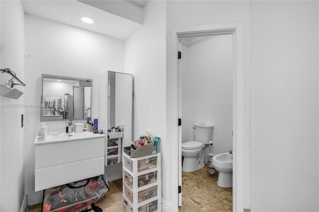 bathroom with toilet, a bidet, and vanity