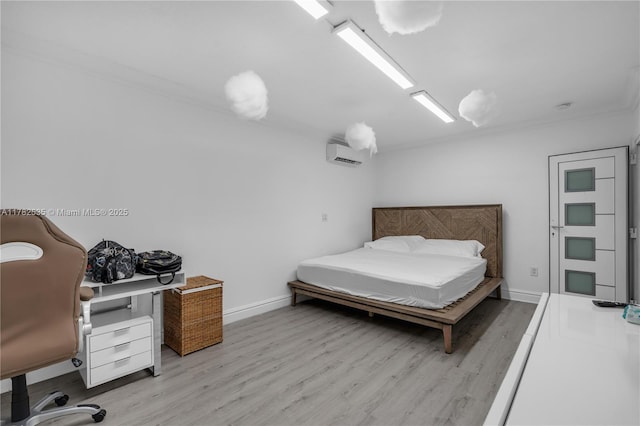 bedroom featuring ornamental molding, baseboards, a wall mounted AC, and wood finished floors