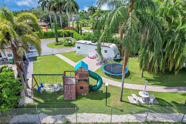 view of property's community featuring a trampoline, a yard, fence, and playground community