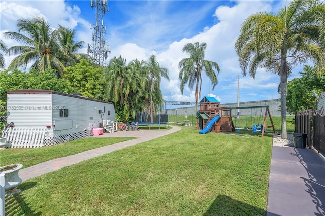 view of yard with a trampoline, fence, and a playground
