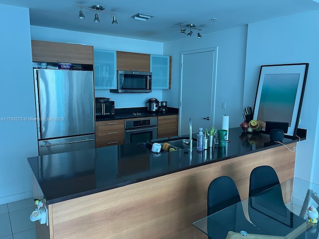 3301 NE 1st Ave Unit H1810, Miami, FL 33137 - kitchen with dark countertops, stainless steel appliances, a kitchen bar, tile patterned flooring, and modern cabinets