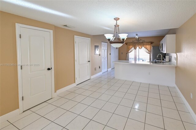 8390 NW 103rd St Unit 205H, Hialeah Gardens, FL 33016 - kitchen featuring visible vents, hanging light fixtures, a chandelier, a textured ceiling, and white cabinetry