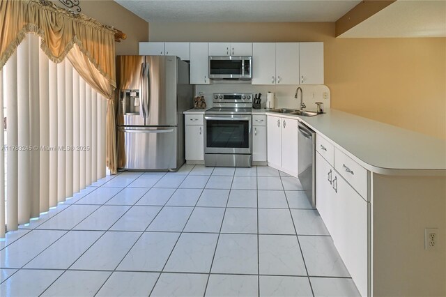 8390 NW 103rd St Unit 205H, Hialeah Gardens, FL 33016 - kitchen featuring a peninsula, white cabinetry, light countertops, a sink, and stainless steel appliances