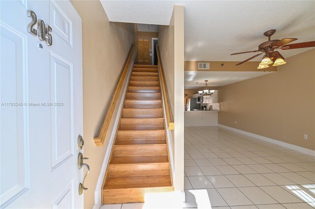8390 NW 103rd St Unit 205H, Hialeah Gardens, FL 33016 - staircase with baseboards, tile patterned floors, a textured ceiling, visible vents, and ceiling fan with notable chandelier