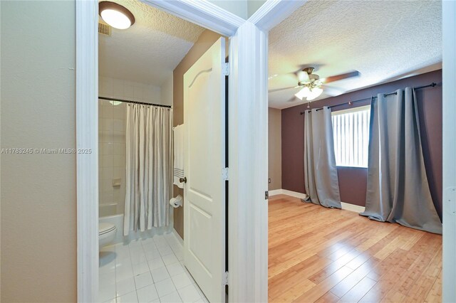 8390 NW 103rd St Unit 205H, Hialeah Gardens, FL 33016 - bathroom with baseboards, a textured ceiling, toilet, shower / bathtub combination with curtain, and ceiling fan