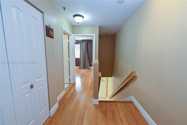 8390 NW 103rd St Unit 205H, Hialeah Gardens, FL 33016 - hall with a textured ceiling, light wood finished floors, baseboards, and an upstairs landing