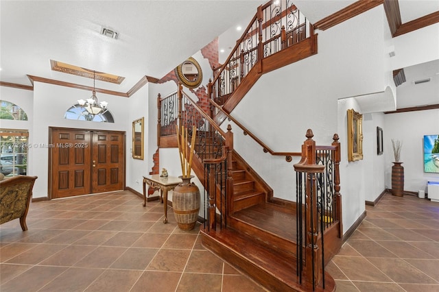 tiled foyer entrance featuring a high ceiling, ornamental molding, visible vents, and stairway