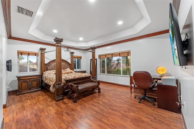 bedroom with visible vents, baseboards, a raised ceiling, and multiple windows