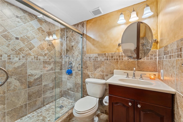 full bathroom with a shower stall, vanity, visible vents, toilet, and tile walls