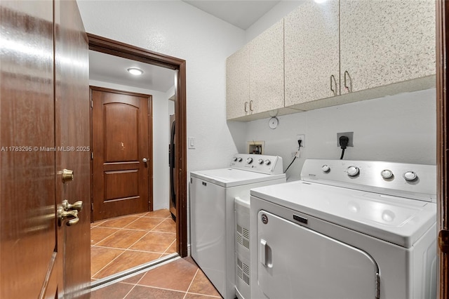 laundry area featuring washer and dryer, light tile patterned flooring, and cabinet space