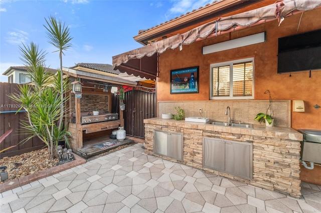 view of patio with a sink, grilling area, fence, a gate, and an outdoor kitchen