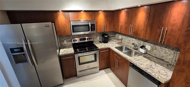 2801 NE 183rd St Unit 714W, Aventura, FL 33160 - kitchen with appliances with stainless steel finishes, a sink, light stone countertops, light tile patterned floors, and decorative backsplash