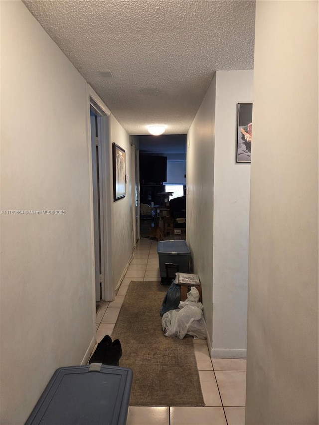 hallway featuring a textured ceiling and light tile patterned flooring