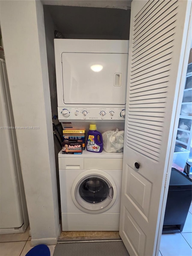laundry room featuring tile patterned flooring, stacked washer / dryer, and laundry area