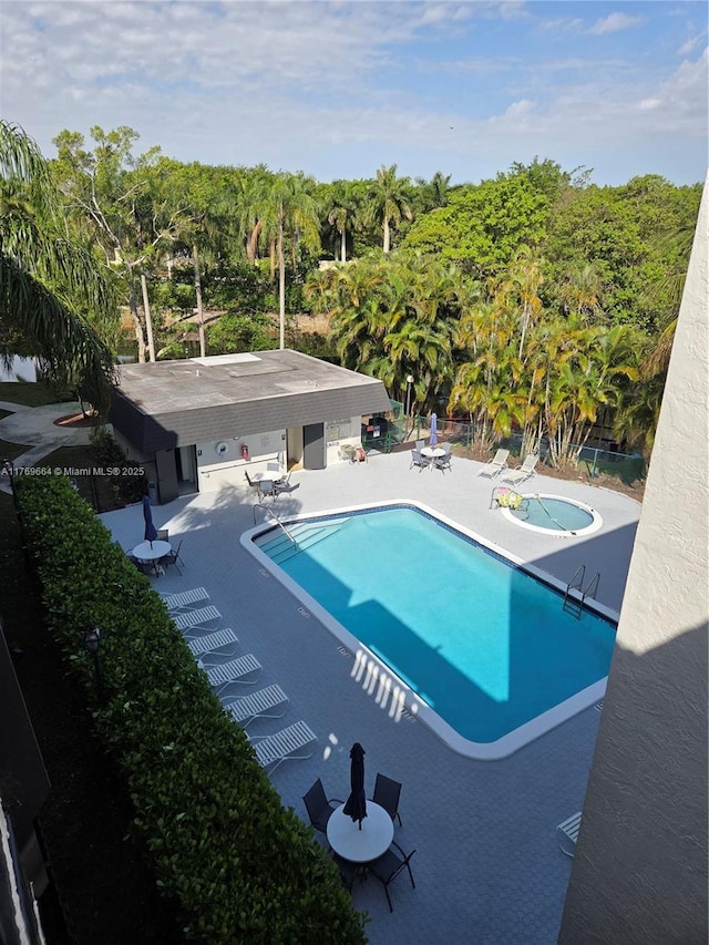 pool with fence, a patio, and a hot tub