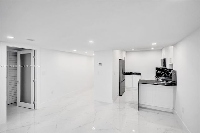 interior space featuring white cabinets, marble finish floor, baseboards, and freestanding refrigerator