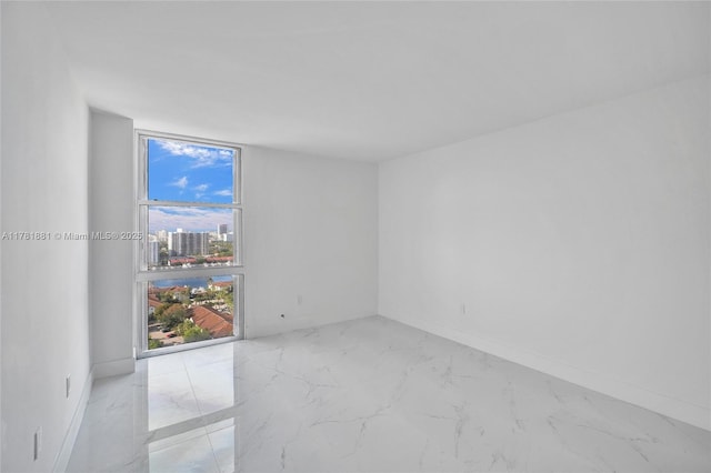 unfurnished room featuring marble finish floor and baseboards