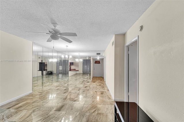 hall with marble finish floor, visible vents, a textured ceiling, and baseboards