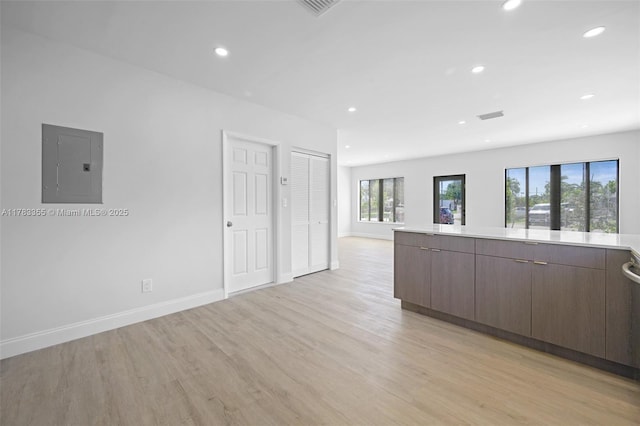 interior space with electric panel, recessed lighting, light wood finished floors, and baseboards