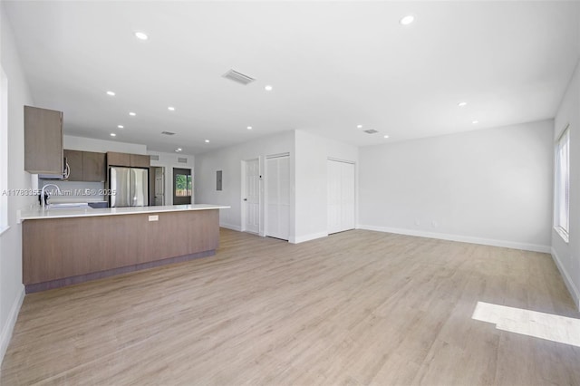 unfurnished living room featuring visible vents, baseboards, a sink, recessed lighting, and light wood-style flooring
