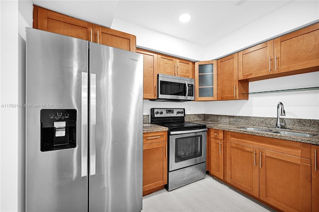 1845 W 73rd Pl Unit 1845, Hialeah, FL 33014 - kitchen with appliances with stainless steel finishes, a sink, dark stone countertops, brown cabinetry, and glass insert cabinets