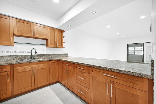 1845 W 73rd Pl Unit 1845, Hialeah, FL 33014 - kitchen featuring dark stone counters, a sink, brown cabinetry, recessed lighting, and light wood-style flooring