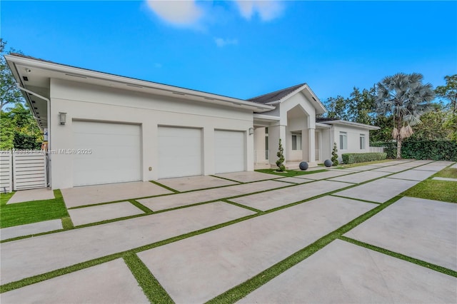 ranch-style house with fence, a garage, driveway, and stucco siding