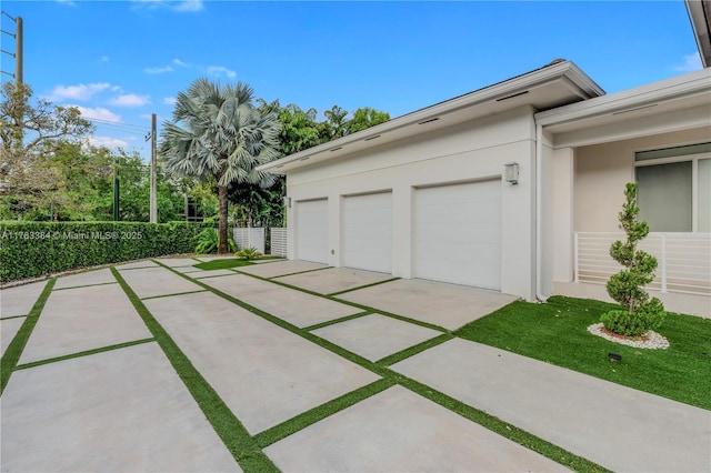 garage featuring fence and concrete driveway