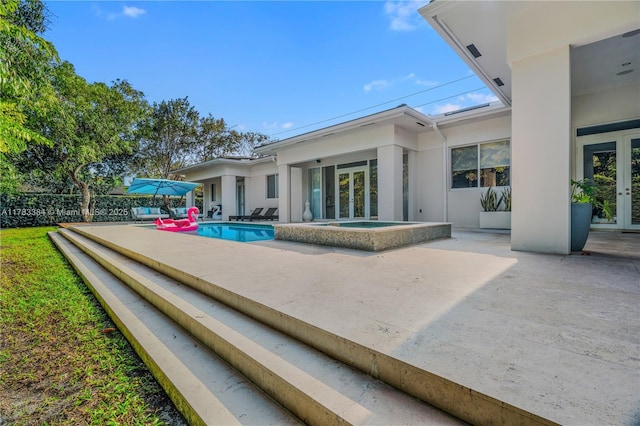 back of house featuring a patio, french doors, stucco siding, and an in ground hot tub