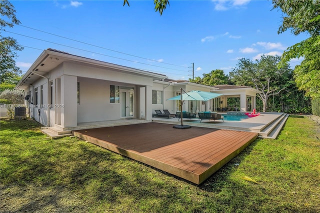 back of property with central AC unit, a lawn, stucco siding, an outdoor pool, and a wooden deck