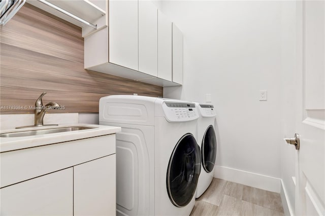 laundry area featuring washing machine and dryer, baseboards, a sink, and cabinet space
